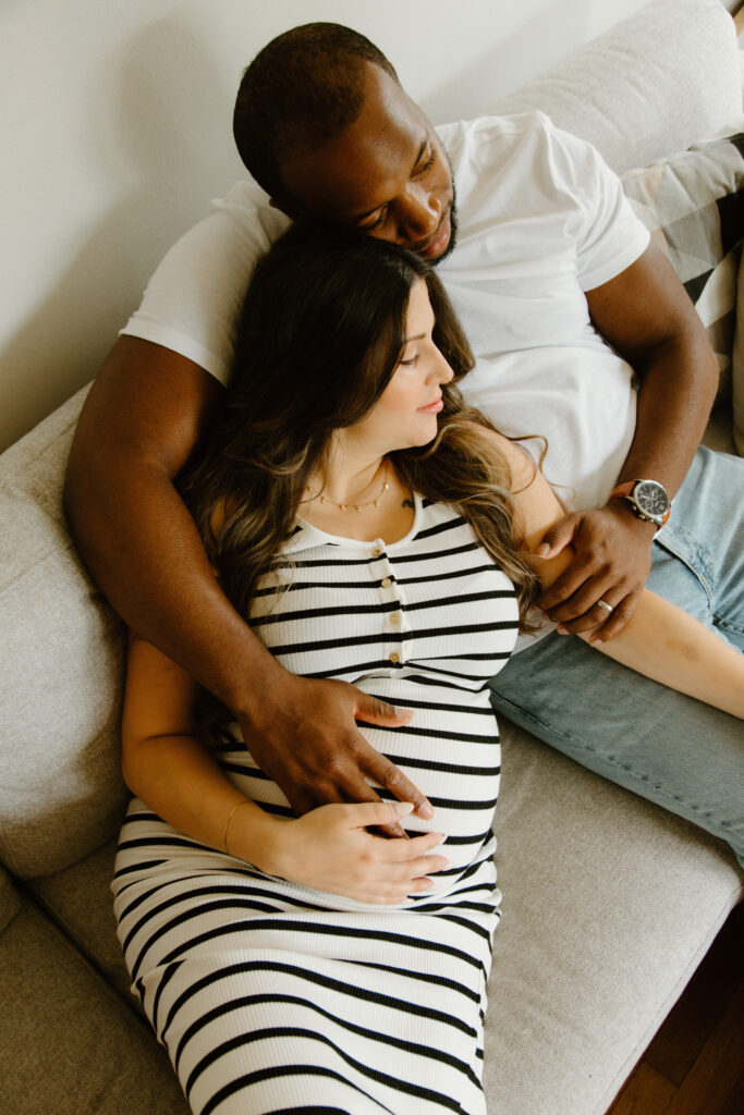 Couple sitting together on the couch during an in-home maternity session.