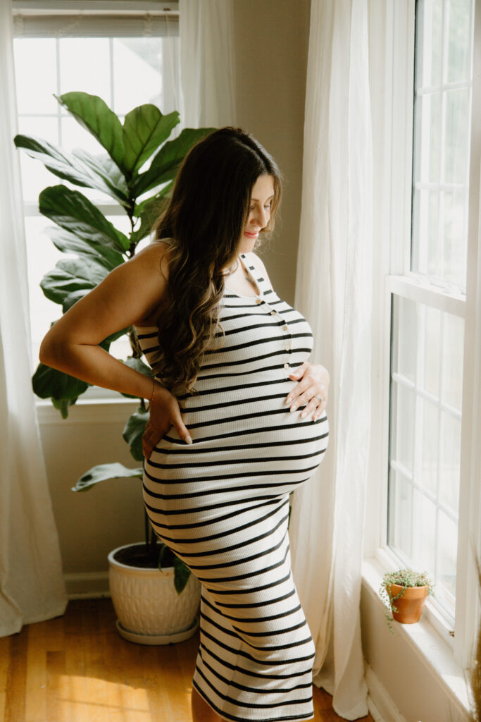 Expectant mother standing in her home during a Grand Rapids maternity photography session.