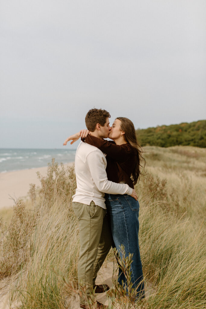 Newly engaged couple embracing near the Lake Michigan shoreline.