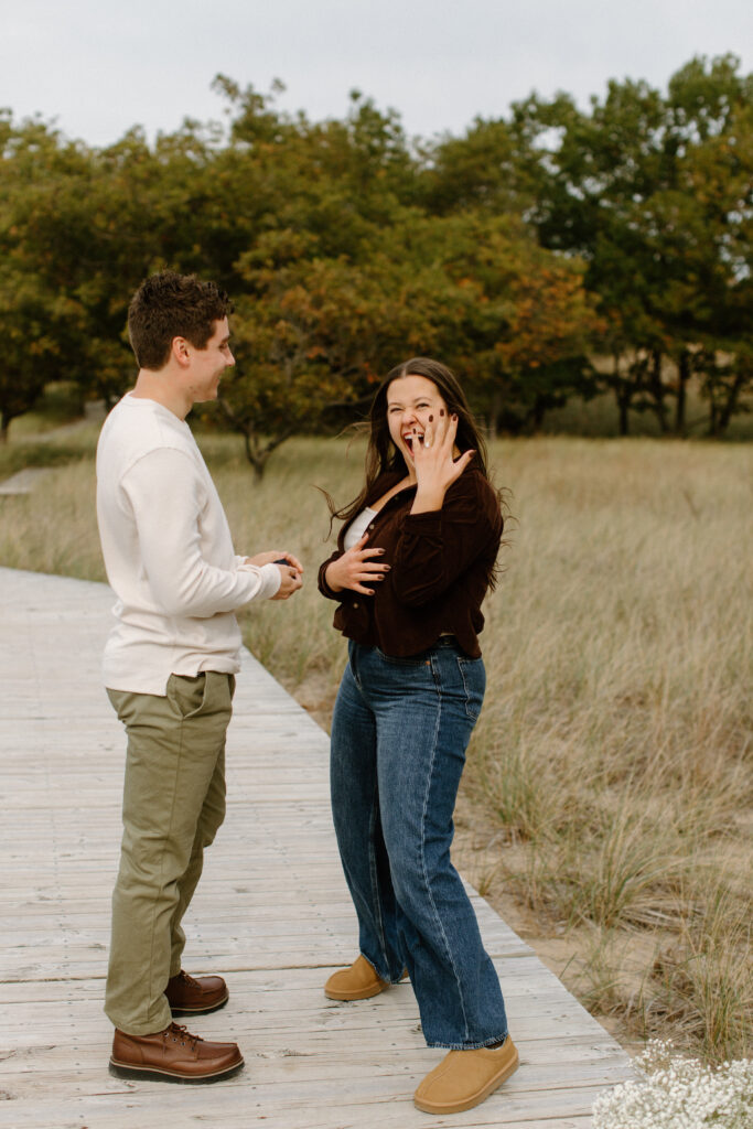 Newly engaged couple celebrating after a proposal overlooking Lake Michigan.