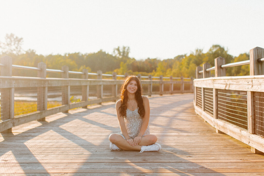 High school senior sitting on bridge during session.